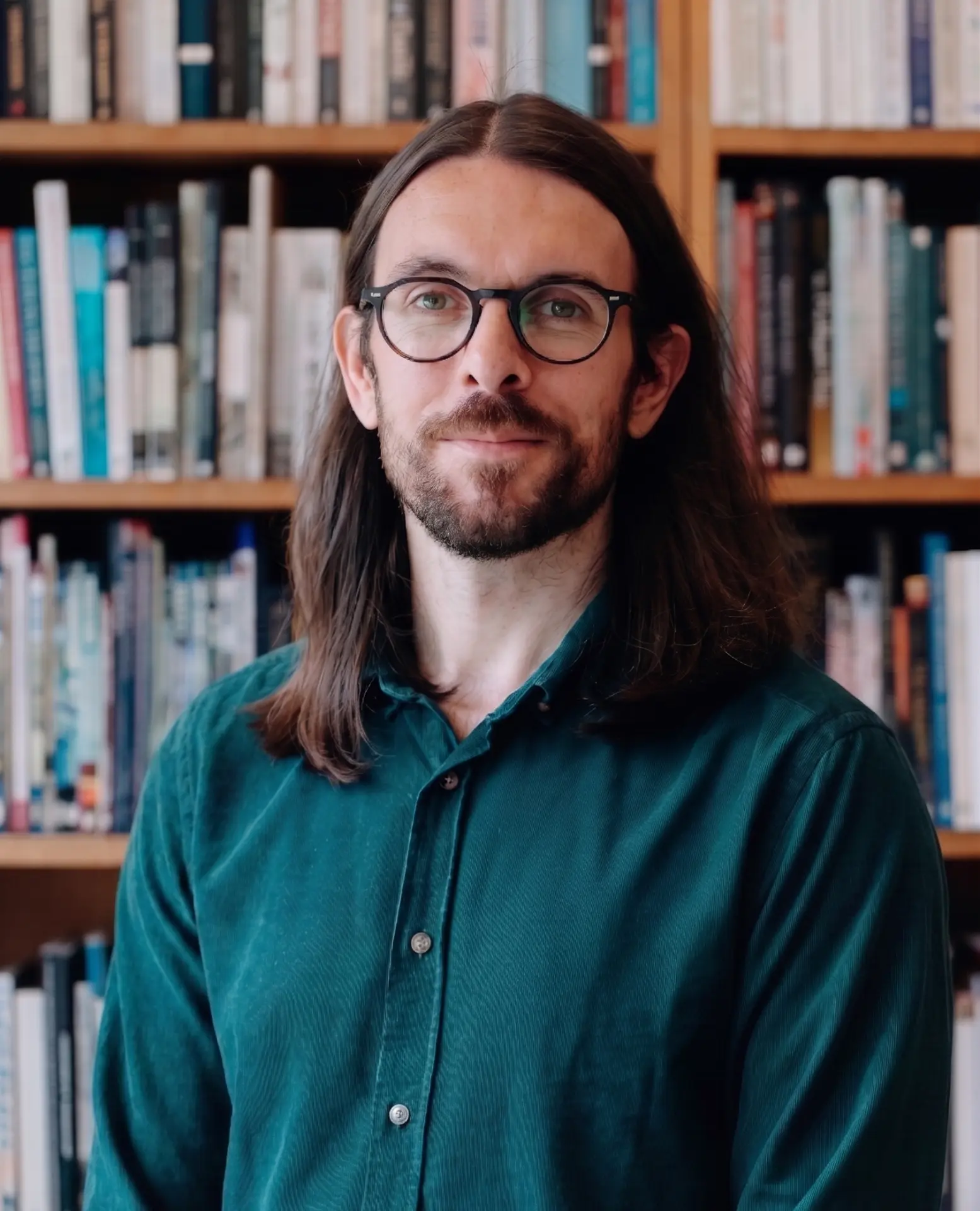 Portrait of Max Dunne in front of a bookshelf